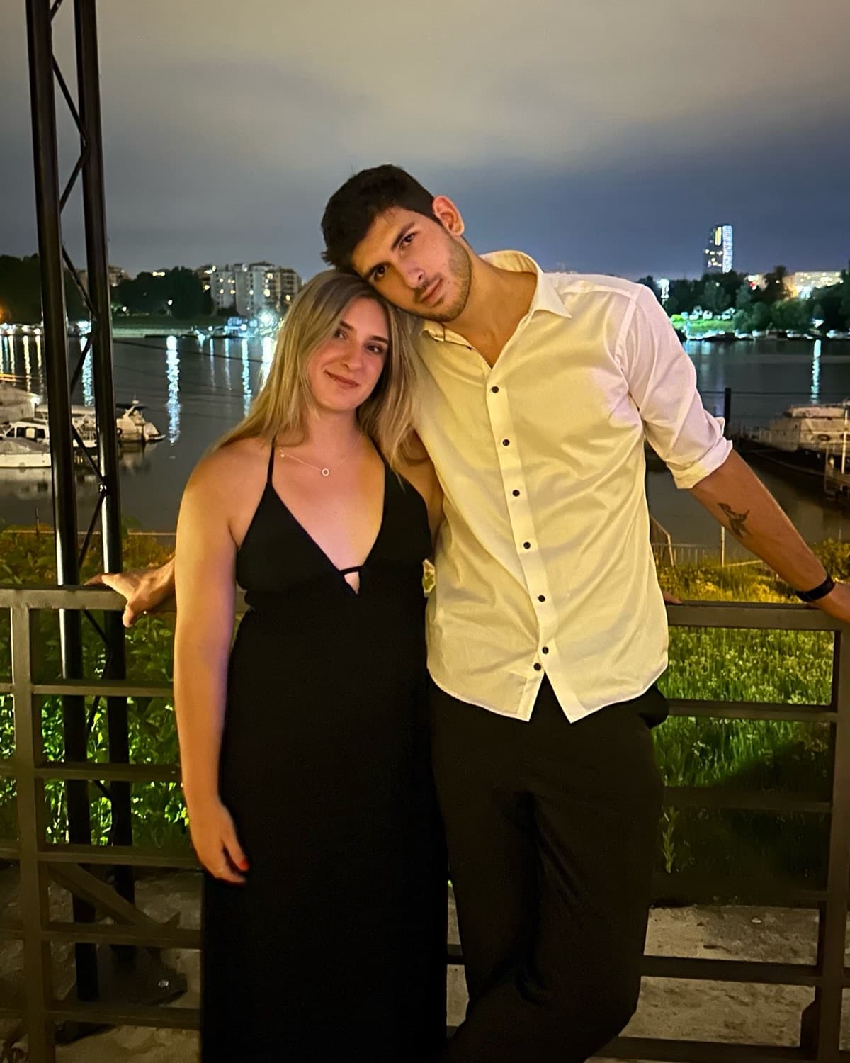Lisa and Marko by the river at night, with the lights of Belgrade behind them