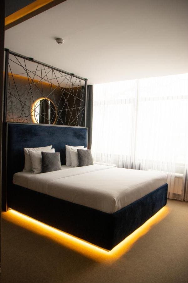 A double room with a navy velvet headboard and a large window