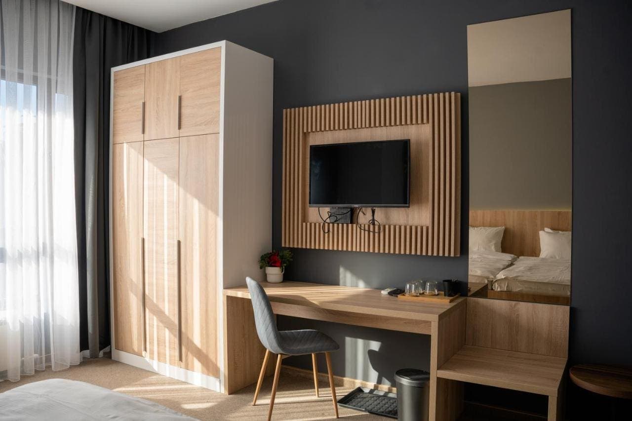A room with a wardrobe, desk, and wall-mounted TV