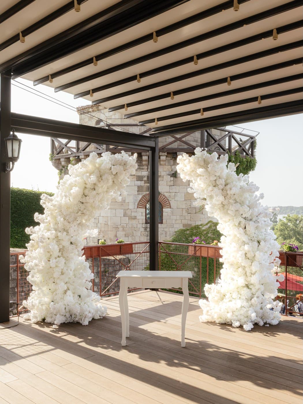 A white floral ceremony arch on the fortress terrace