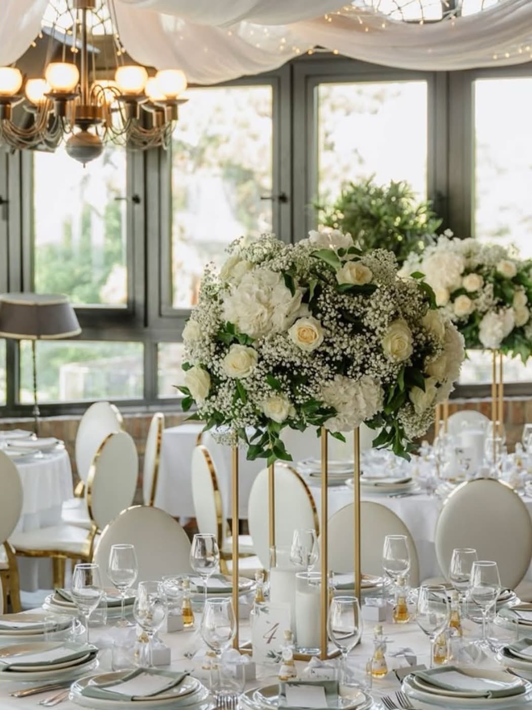 Round tables in the conservatory under draped fabric and fairy lights