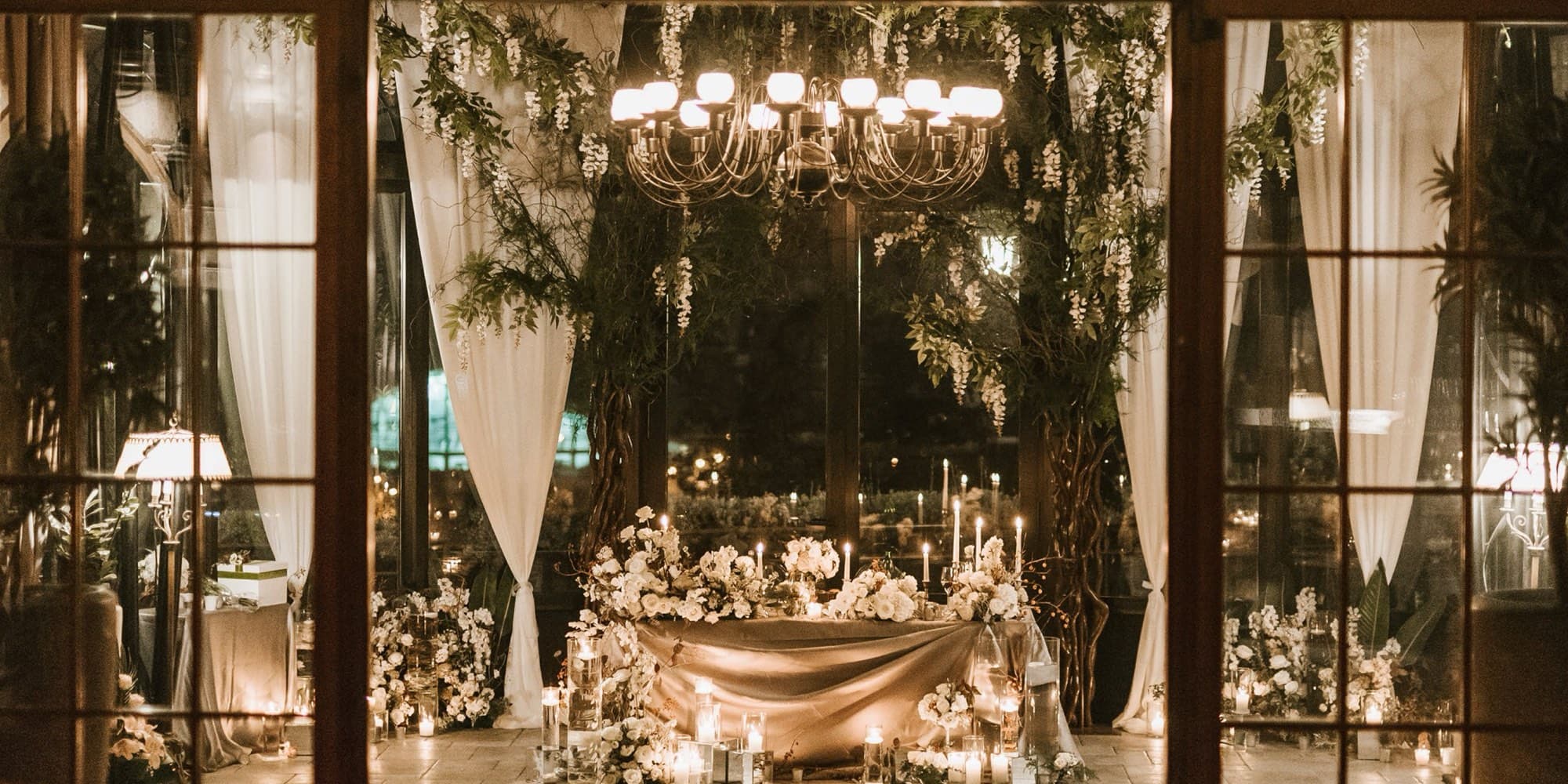 The glass conservatory at Kalemegdanska Terasa at night, lit by candles and a chandelier