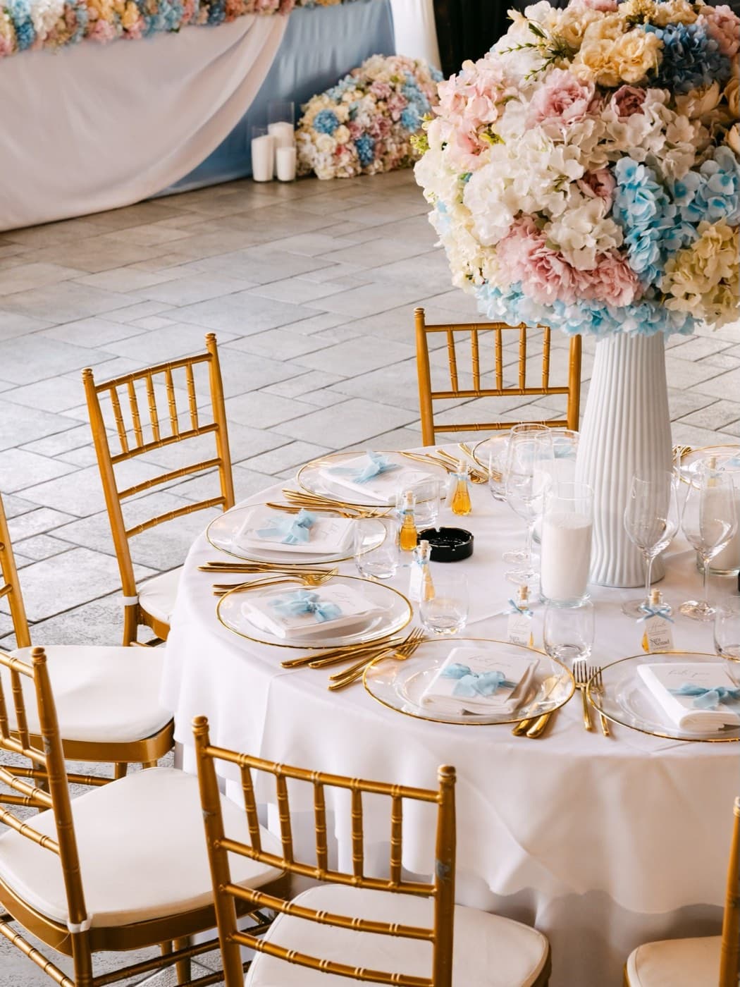 A round table set with gold chairs and pastel flowers